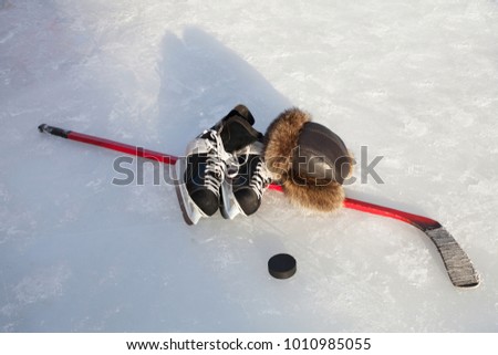 Hockey skates, stick and puck on natural ice.