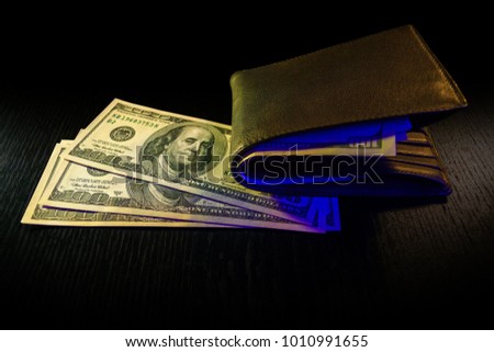 wallet with dollar banknotes on black wooden table