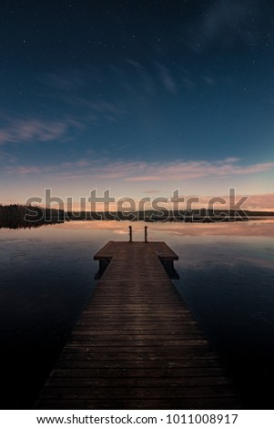 Savojarvi lake at midnight lit by moonlight and a pier on foreground in Kurjenrahka National Park, Finland