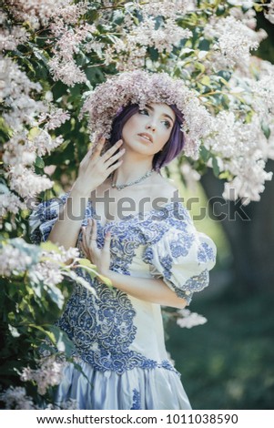 Young woman in beautiful vintage dress posing in spring garden.