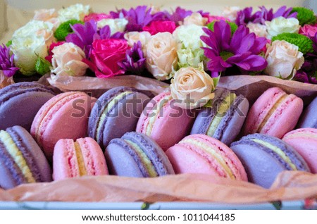 French macaroon cake. Violet and pink macaroons in a box with flowers on the bed.