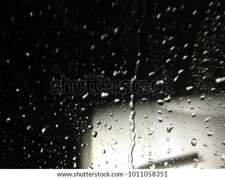 a part of aircraft wing with dark black sky background focusing on rain drop on the window as a foreground
