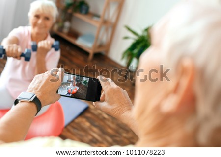 Senior couple exercise together at home taking pictures on exercise ball