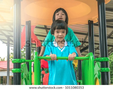 Child play on playground concept. Asian girl child play standing on slider in playground park in school on morning