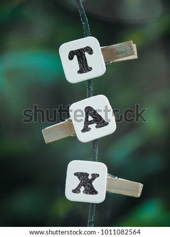 Concept image of TAX winth hanging alphabets on tree over nice green background