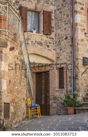 Traditional stone house with an empty chair on the front patio,  taken in a quint Italian village in Tuscany.