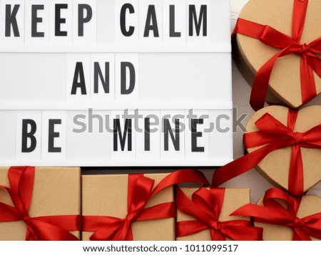 KEEP CALM AND BE MINE word on lightbox on knit background with wrapped gifts boxes. Valentine's day concept.