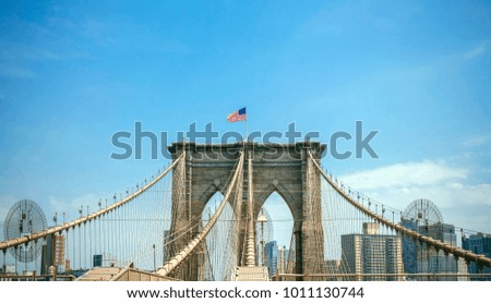 View of Brooklyn Bridge towers over blue sky with Manhattan skyline on background, in New York City