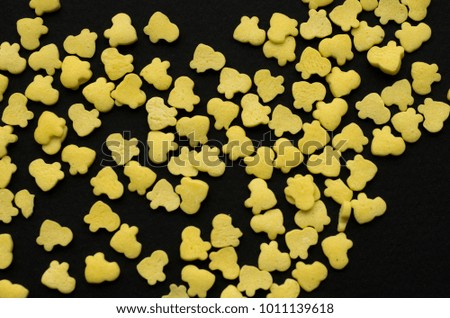 sprinkle for a cake in the form of yellow chickens on a black matte background