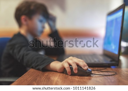 Little addicted boy playing video game on laptop at home Royalty-Free Stock Photo #1011141826