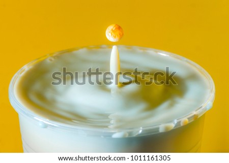 High speed studio photograph of milk drop on yellow background
