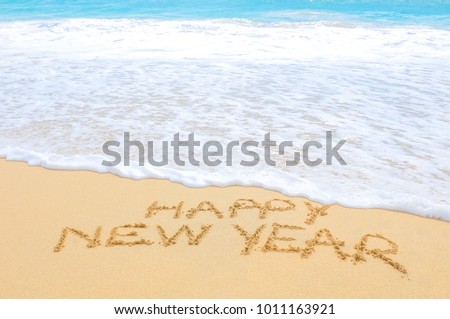 Happy New Year written on sand of an exotic beach