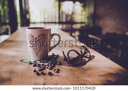 Valentine's Day for Coffee Lovers, a cup of black coffee sharing on the wooden table in the morning lighting with feeling romance and hipster vintage style,with some coffee beans and heart,copy space.