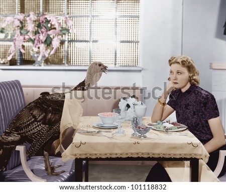 Woman eating meal at table with live turkey