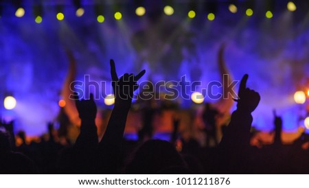 Metal fans enjoying concert with rock'n'roll sign up in the air