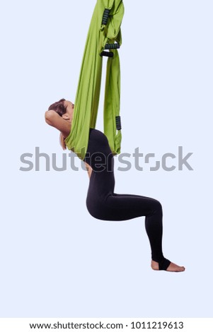 Young woman doing aerial yoga in green hammock.