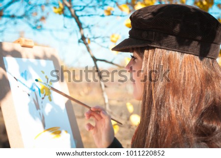Portrait of a young beautiful woman with a brush in her hand, outdoors