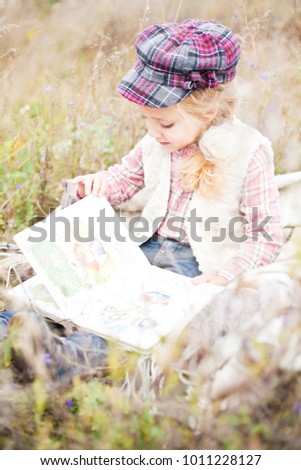 Cute little girl reading book on nature