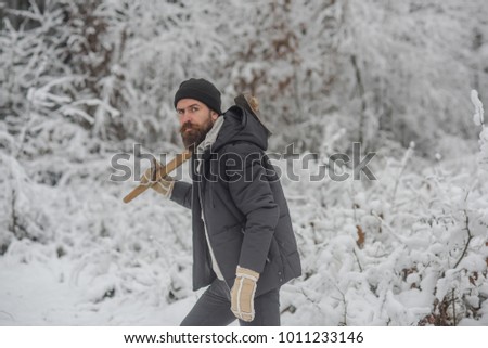 Bearded man with axe in snowy forest. Temperature, freezing, cold snap, snowfall. skincare and beard care in winter, beard warm in winter. Camping, traveling and winter rest. Man lumberjack with ax.