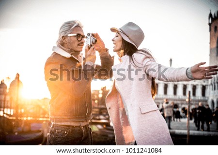 Beautiful couple in Venice, Italy - Lovers taking pictures with a vintage styled camera and having fun in Saint Mark Square, Venice