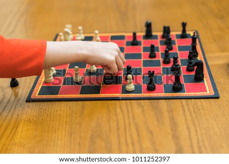 The child's hand rearranges the chess piece. Mental development of the child