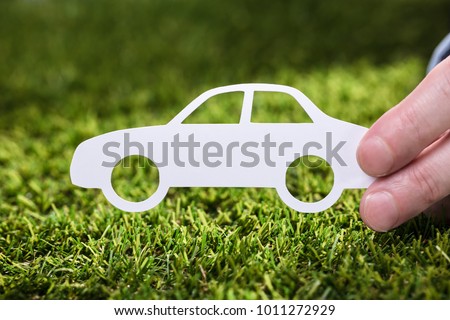 Close-up Of A Person's Hand Holding White Paper Car On Green Grass