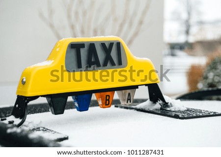 Side view of yellow Taxi sign covered with snow on a cold winter day