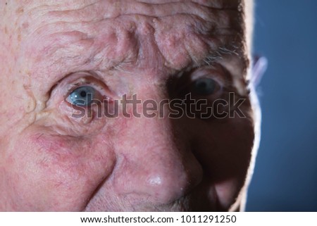 Very old 92 years man portrait. Grandfather sad and depressed. Aged, elderly, loneliness, senior. Macro blue eyes of man sitting alone.