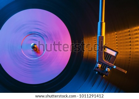 Movie of retro-styled record player spinning vinyl black record. Cinemagraph. Side view. Beautiful neon night colors. Royalty-Free Stock Photo #1011291412