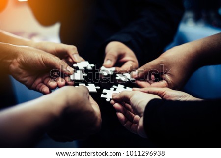 Close-up photo of businesspeople holding jigsaw puzzle