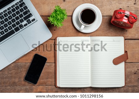 View from above.Laptop,clock,notebook,smartphone and cup of coffee on wooden desk.