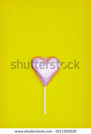 Pink heart chocolate shape on yellow paper background. minimal love concept