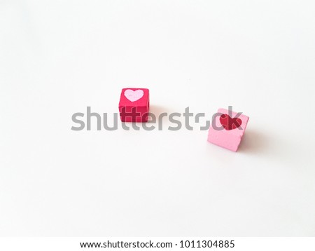 Wooden beads in cubic that are painted in heart shape on white background. It's for Valentines theme that refer about love and couple.