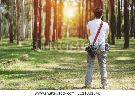 Photographer holding camera in the pine tree forest during journey