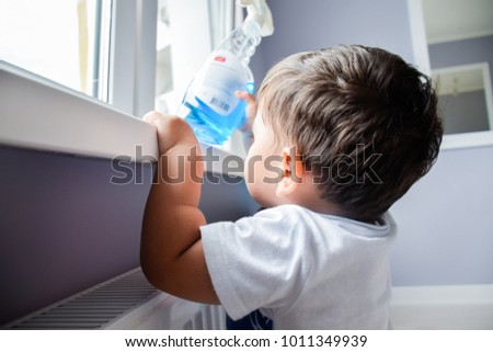 Little latin boy reaching a toxic cleaning product. Royalty-Free Stock Photo #1011349939