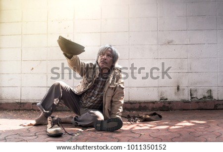 homeless and hungry vagrant holding a cup, asking for money and food Royalty-Free Stock Photo #1011350152