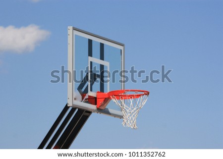 A shot of a Basket Ball backboard that is bright and colorful with a blue sky and one lonely cloud in Hutchinson Kansas.