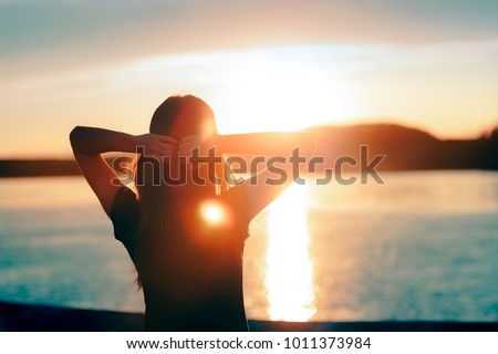 Happy Hopeful Woman Looking at the Sunset by the Sea. Silhouette of a dreamer girl looking hopeful at the horizon
