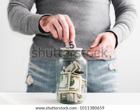 Man on the background of a piggy bank in the form of a jar with money inside
