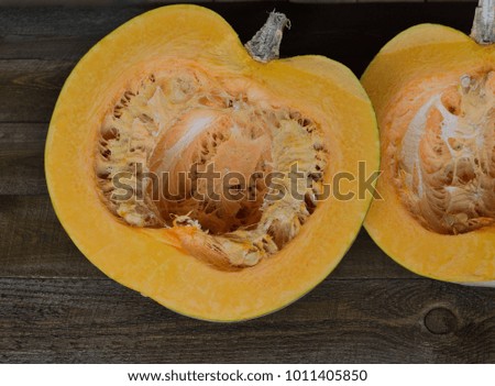two parts of big  orange pumpkin with seeds on the dark wooden table 
