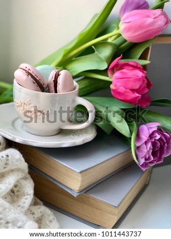tulips on books with cup with macaroons. concept reading wallpaper. 