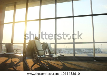 Empty chairs and passenger in the airport terminal on evening sunset light