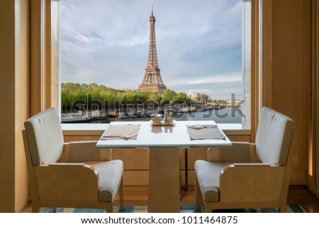 Modern luxury restaurant interior with romantic sence Eiffel Tower and Seine river view in Paris, France. Dinning table in restaurant at Paris, France.