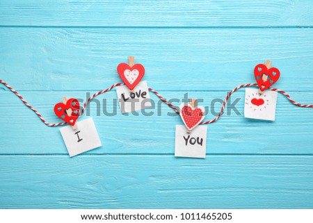 Rope with paper hearts and phrase "I love you" on wooden background