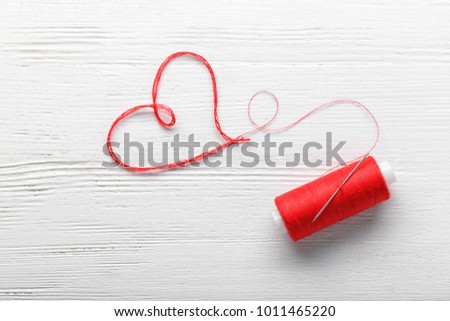 Heart made of thread on wooden background