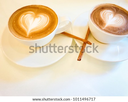 Coffee for couple/ lovers concept. Valentine's day theme. Cappuccino or latte coffee with heart latte art on white modern style table. Stylish and modern. Closeup, Selective Focus.