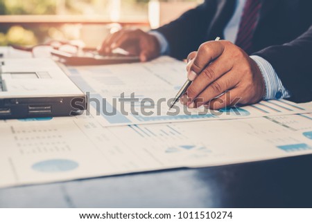 A businessman analyzing investment charts and using a calculator for calculate profit and loss in his workplace. Business concept.