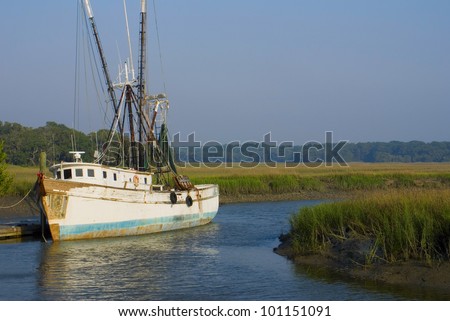 An old shrimp boat docked in a marshy grassland Royalty-Free Stock Photo #101151091