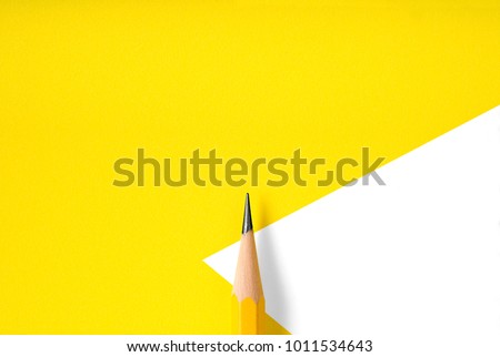 Minimalist template with copy space by top view close up macro photo of wooden yellow pencil isolated on yellow paper and combine with white shape. Flash light made smooth shadow from pencil. Royalty-Free Stock Photo #1011534643