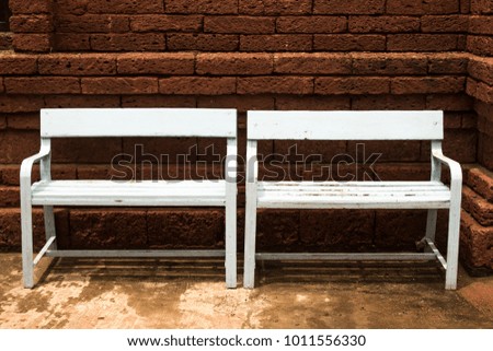 Wooden bench on red brick wall background